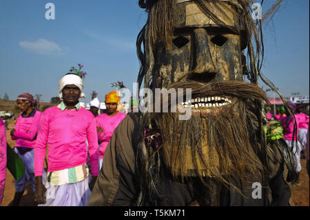 Tribal uomo che indossa una maschera di legno. + Danzatori tribali. Tutti loro appartengono a una cultura tribale gruppo che sta eseguendo danze a una fiera locale ( India) Foto Stock