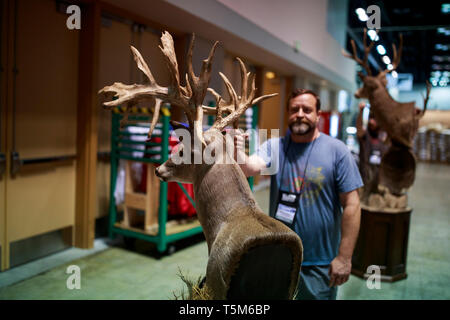 Lavoratori spostare un cervo ripiene durante l'impostazione per le ANR convenzione. Preparare i fornitori di stand nel padiglione espositivo prima che la National Rifle Association (NRA) convenzione presso la Indiana Convention Center nel centro di Indianapolis. Foto Stock