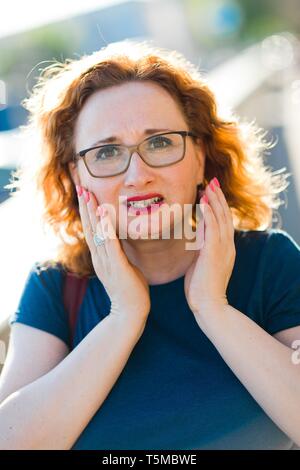 Donna attraente sulla sensazione di strada improvviso mal di denti - disagio gesti con le mani Foto Stock