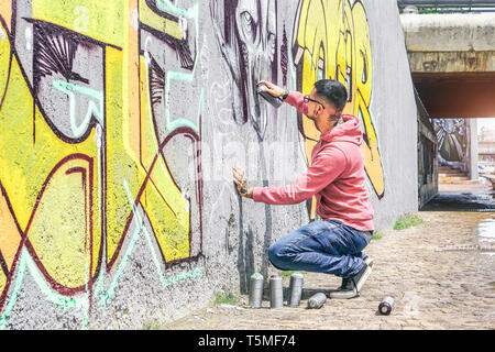 Street Graffiti artist pittura con un colore spray può un mostro scuro cranio graffiti sul muro della città per esterno Foto Stock