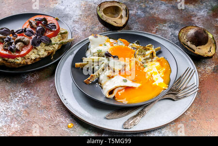 Una gustosa prima colazione. Sandwich con pomodori e funghi, avocado, uova fritte con asparagi. Foto Stock