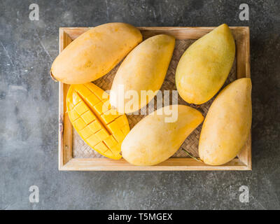 Diversi dolci fresche Thai Giallo mango su un vassoio di legno su sfondo grigio. vista superiore Foto Stock