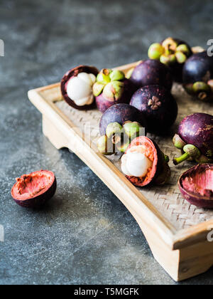 Regina tailandese di frutta - Mangosteen è frutta organica sul vassoio in legno Freschi mangostani su sfondo grigio. Messa a fuoco selettiva. Foto Stock