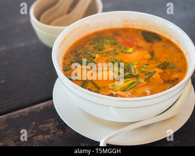 Amaro e piccante Tom Yum Goong zuppa su un tavolo in un ristorante. Tailandese tradizionale cibo. Autentica tradizionale zuppa tailandese Tom Yam su un tavolo di legno Foto Stock