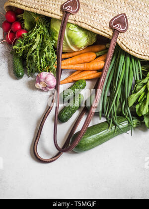 Paglia di vimini sacchetto pieno di naturali freschi ortaggi di primavera. Un sano vegetariano vegano cibo dal mercato locale dalle aziende agricole Foto Stock