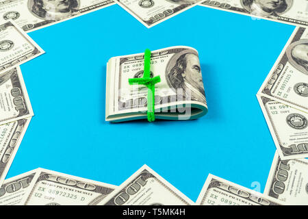 Le fatture del dollaro piegato a metà su fondo azzurro Foto Stock