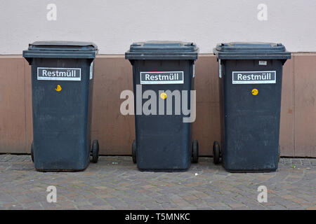3 piccolo residuo nero cestini portarifiuti su ruote in piedi in fila sul muro di casa in città Foto Stock
