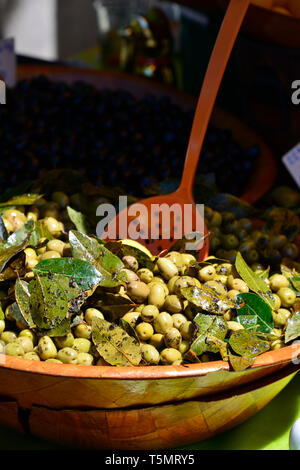 Una vista verticale di olive verdi e foglie e un mestolo di legno in un mercato francese. Foto Stock