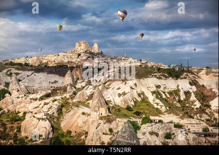 I palloni ad aria calda volando sopra la Cappadocia vicino Castello di Uchisar presso sunrise, Turchia Foto Stock