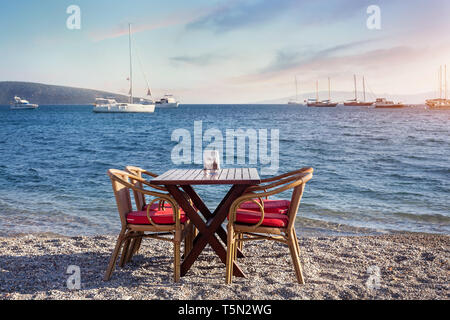 Carino tavolo e sedie e ombrellone in spiaggia al ristorante sul mare a bodrum, Turchia Foto Stock