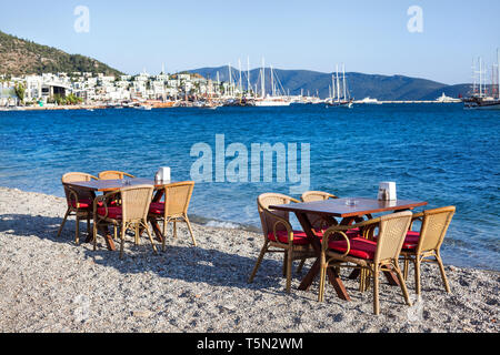 Carino tavolo e sedie e ombrellone in spiaggia al ristorante sul mare a bodrum, Turchia Foto Stock