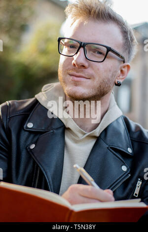 Ritratto di smart guy creatore in abiti casual rende note in un notebook Foto Stock