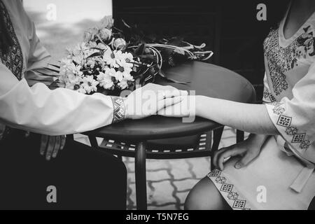 Man mano tesa della donna al tavolo in ucraino abiti tradizionali. Foto in bianco e nero. Foto Stock