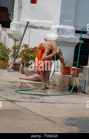 Luang Prabang, Laos - Marzo 23, 2019 : Monaco lavaggio con tubo flessibile da giardino al di fuori del tempio a Luang Prabang, Laos. Foto Stock