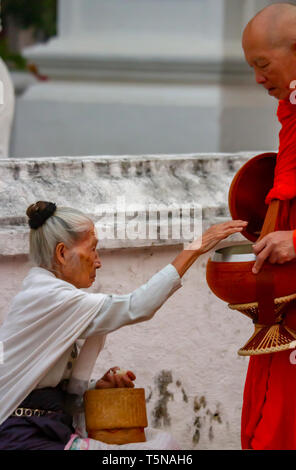 Luang Prabang, Laos - Marzo 24, 2019 : donna locale dando cibo offrendo al monaco buddista di prima mattina. Foto Stock