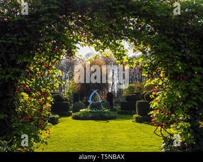 Il giardino bianco e la scultura a Chenies Manor, Buckinghamshire in aprile sunshine bello fresco verde prato, incorniciato da akebia, Cioccolato Vine. Foto Stock