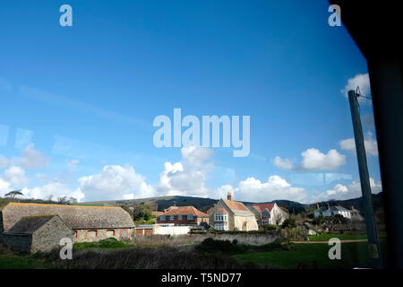 Un idilliaco paesaggio inglese farm e il borgo vista scena dal passaggio di un finestra di bus. Cielo blu e soffici nuvole bianche appaiono come treno a vapore soffi. Foto Stock