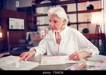 Donna che indossa camicia bianca leggendo il libro avente tempo libero Foto Stock