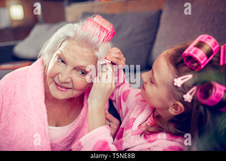 Bella ragazza carina mettendo a forcina per capelli sui suoi bellissimi granny Foto Stock