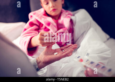 Ragazza in accappatoio rosa assunzione di pillole da granny mentre la sensazione di malessere Foto Stock