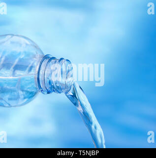 Profondità di campo. Soft focus di blu bottiglia versando acqua contro fresco e sfondo bluastro. Foto Stock