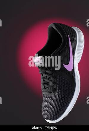 Una vita ancora immagine di un Nike Sport femminile scarpa, floating davanti a uno sfondo viola Foto Stock