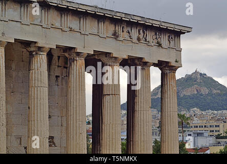 Dettaglio del tempio di Efesto ad Atene, in Grecia. La collina di Lycabettus e city building in background. Foto Stock