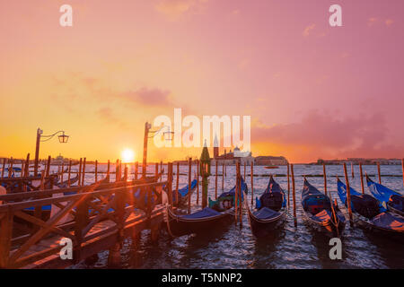 Italiano tradizionale di gondole attraccate ai poli in Europa Venezia vicino al centro della città e la Piazza San Marco con una vista sullo sfondo della chiesa di S Foto Stock