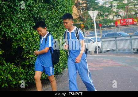 Shenzhen, Cina: gli studenti delle scuole elementari e medie a piedi sulla strada verso casa dopo la scuola nel pomeriggio Foto Stock