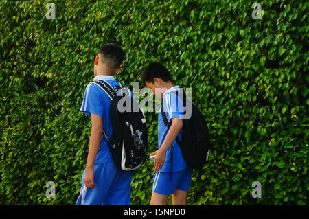 Shenzhen, Cina: gli studenti delle scuole elementari e medie a piedi sulla strada verso casa dopo la scuola nel pomeriggio Foto Stock