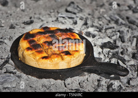 Delizioso formaggio Provolone argentino formaggio filato (Provoleta) che viene cucinato in una padella in ghisa alla brace e cenere, Buenos Aires, Argentina. Foto Stock