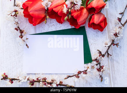 Un bouquet di tulipani rossi e rami di fiori bianchi contro le schede bianche. Posto per il testo. Il concetto della molla è venuto. Vista da sopra. Banner ma Foto Stock