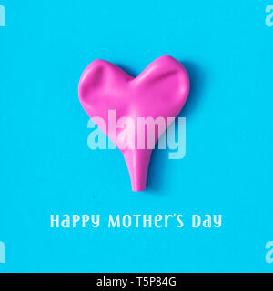 Un sgonfiato rosa a forma di cuore e di palloncino il testo felice festa della mamma su uno sfondo blu Foto Stock