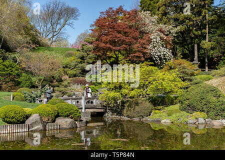 I visitatori a piedi su un ponte per il giapponese Hill-e-laghetto in giardino Brooklyn Giardino botanico di Brooklyn, a New York il 24 aprile 2019. Foto Stock