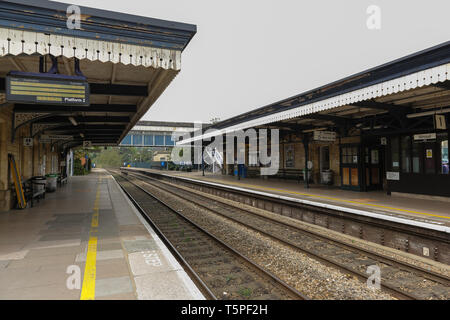 STROUD, Inghilterra - Aprile 23, 2019: grande stazione ferroviaria occidentale nella città di Stroud, cotswolds area.Le piattaforme di vuoto e una passerella di attraversamento tra Foto Stock