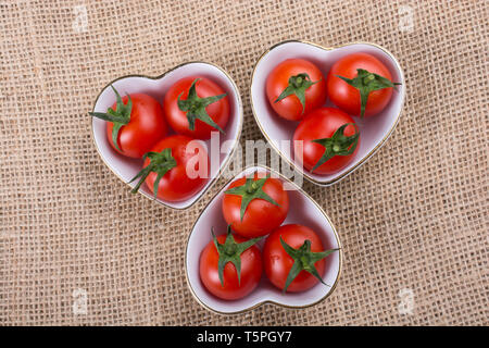 Rosso ciliegia matura di pomodori Pomodori nel cuore ciotola sagomata Foto Stock