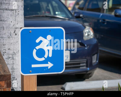 Sedia a rotelle segno di traffico rivolta verso destra in un parcheggio Foto Stock