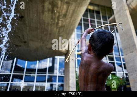 Brasilia, Brasile. 26 apr, 2019. Miguel, un bambino Munduruku, punti da una freccia e arco presso il Ministero della giustizia a massicce proteste da parte delle popolazioni indigene a Brasilia per proteggere il loro habitat. Presidente Bolsonaro vuole ridurre la protezione della regione amazzonica e utilizzare la foresta pluviale più economicamente. Credito: Pablo Albarenga/dpa/Alamy Live News Foto Stock