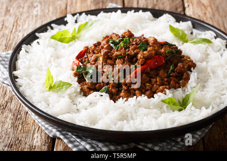 Rosolare il pollo di basilico con peperoncino e la salsa di soia con un lato piatto di riso close-up su una piastra sul tavolo orizzontale. Foto Stock