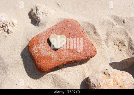 Cuore pietra sagomata su di una spiaggia di sabbia Foto Stock