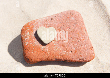 Cuore pietra sagomata su di una spiaggia di sabbia Foto Stock