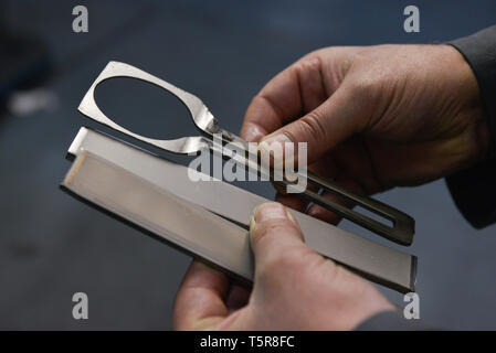 Guy Degrenne nella factory di Vire (Normandia, a nord-ovest della Francia), specializzata nella posateria e argenteria. Acciaio inossidabile argenteria workshop: lavoratore hol Foto Stock