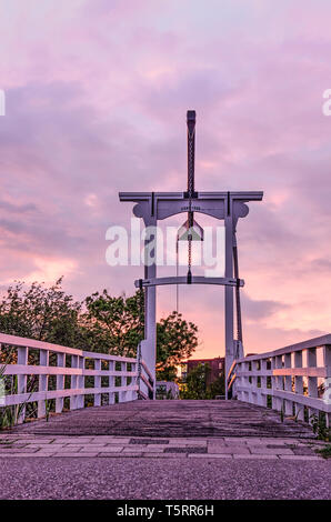 Bianco tradizionale ponte levatoio in legno attraverso un canale olandese con una spettacolare violaceo cielo nuvoloso alla backgroound Foto Stock