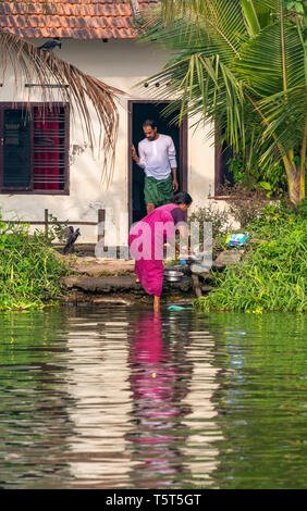 Ritratto verticale di una signora preparandosi il cibo sulla riva del fiume in Alleppy, India Foto Stock