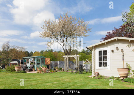 Giardino inglese in rurale Anglia Est in Norfolk. All'esterno grande giardino privato con alberi Potting Shed summerhouse e. Prato e aiuole di fiori in sp Foto Stock