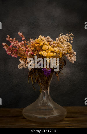 Bouquet di fiori secchi dimenticato nel soppalco su sfondo scuro Foto Stock