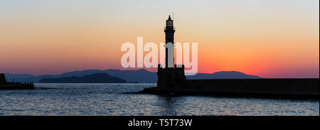 La silhoutte del faro nel porto di Chania, una città sull'isola di Creta, Grecia durante il tramonto. Foto Stock