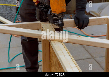 Lavoratore di installare il pavimento di legno per la martellatura su un deck patio backyard Foto Stock