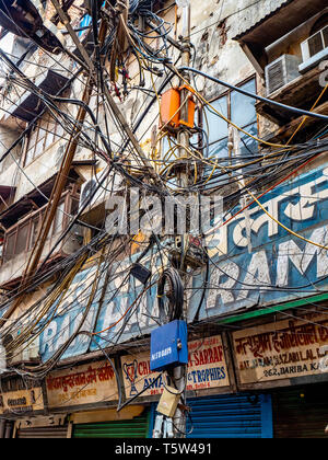 Caotico groviglio di fili per illuminazione stradale le forniture di elettricità e i cavi telefonici in una strada della città vecchia di Delhi India del Nord Foto Stock