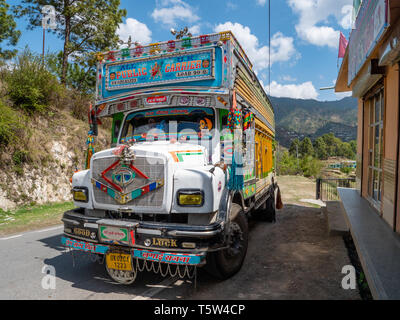 Colorfully verniciato e riccamente decorate le merci pesanti camion su una strada attraverso la regione di Binsar di Uttarakhand India del Nord Foto Stock